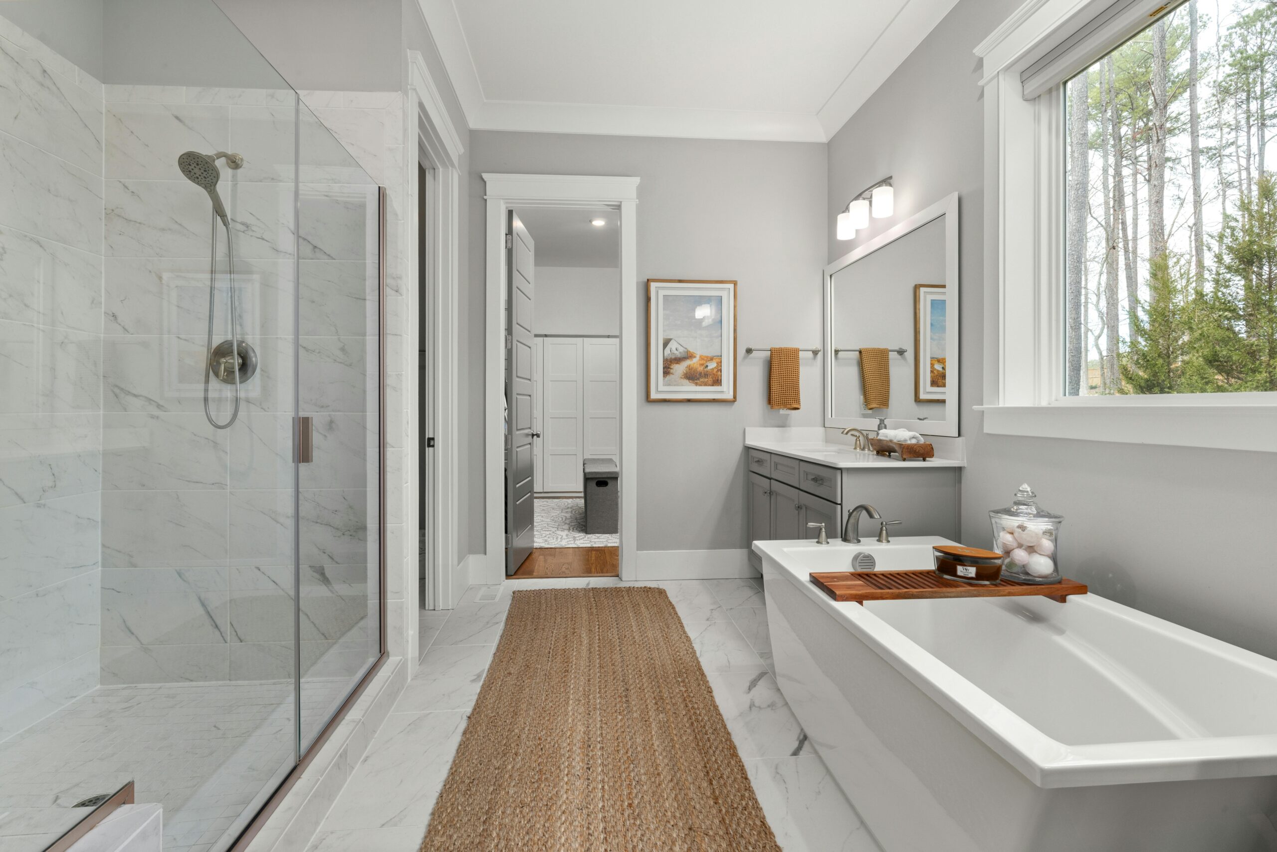Home Elegant bathroom with a freestanding bathtub, glass shower, and large window view.